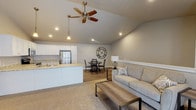 Located in Sister Bay, Wisconsin, this single-floor unit offers a thoughtfully designed layout with a neutral, contemporary aesthetic throughout. The open-concept main living area is anchored by soaring vaulted ceilings and a ceiling fan, creating an airy, spacious feel. The living room features plush carpeting and flows directly into the dining area, which is accented by a striking oversized wall clock, and then into the kitchen.

The kitchen is well-equipped with white shaker-style cabinetry, granite-look countertops, stainless steel appliances including a refrigerator, range, and microwave, and a sink peninsula that further connects the space. Wood-look flooring runs throughout the kitchen and dining areas.

The bedroom is generously sized with plush carpeting, a ceiling fan, and a large window that brings in natural light. A secondary room functions as a flexible office or den, complete with a walk-in closet, vaulted ceiling detail, and its own seating area. An additional room with a double bifold closet provides further flexibility.

Two full bathrooms serve the unit, each finished with granite-look vanity countertops, white cabinetry, and wood-look flooring. One features a walk-in shower, while the other includes a soaking tub. A sliding glass door in the living area provides outdoor access and additional natural light.