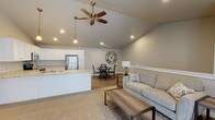 Located in Sister Bay, Wisconsin, this single-floor unit offers a thoughtfully designed layout with a neutral, contemporary aesthetic throughout. The open-concept main living area is anchored by soaring vaulted ceilings and a ceiling fan, creating an airy, spacious feel. The living room features plush carpeting and flows directly into the dining area, which is accented by a striking oversized wall clock, and then into the kitchen.

The kitchen is well-equipped with white shaker-style cabinetry, granite-look countertops, stainless steel appliances including a refrigerator, range, and microwave, and a sink peninsula that further connects the space. Wood-look flooring runs throughout the kitchen and dining areas.

The bedroom is generously sized with plush carpeting, a ceiling fan, and a large window that brings in natural light. A secondary room functions as a flexible office or den, complete with a walk-in closet, vaulted ceiling detail, and its own seating area. An additional room with a double bifold closet provides further flexibility.

Two full bathrooms serve the unit, each finished with granite-look vanity countertops, white cabinetry, and wood-look flooring. One features a walk-in shower, while the other includes a soaking tub. A sliding glass door in the living area provides outdoor access and additional natural light.