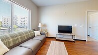 This well-appointed one-bedroom, one-bathroom unit in Oshkosh, Wisconsin offers a thoughtfully designed single-floor layout that maximizes every square foot. The open-concept living and kitchen area serves as the heart of the space, where warm hardwood-style flooring flows throughout. The kitchen is a standout feature, boasting granite countertops, dark espresso cabinetry, black appliances including a refrigerator, range, dishwasher, and built-in microwave, and a peninsula with pendant lighting that doubles as a casual dining bar with seating for two. The adjacent living area is bright and airy, with large windows that invite natural light and offer views of the surrounding neighborhood. The bedroom is a comfortable retreat, carpeted for warmth and featuring a sliding double-door closet for ample storage. A window provides natural light and outdoor views, enhancing the room's welcoming atmosphere. The bathroom continues the design consistency of the unit, with granite countertops, a dark wood vanity, a large mirror, and hardwood-style flooring. A shower-tub combo completes the space. Clean neutral tones and modern finishes throughout give this unit a cohesive, contemporary feel that is both functional and inviting.