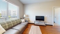 This well-appointed one-bedroom, one-bathroom unit in Oshkosh, Wisconsin offers a thoughtfully designed single-floor layout that maximizes every square foot. The open-concept living and kitchen area serves as the heart of the space, where warm hardwood-style flooring flows throughout. The kitchen is a standout feature, boasting granite countertops, dark espresso cabinetry, black appliances including a refrigerator, range, dishwasher, and built-in microwave, and a peninsula with pendant lighting that doubles as a casual dining bar with seating for two. The adjacent living area is bright and airy, with large windows that invite natural light and offer views of the surrounding neighborhood. The bedroom is a comfortable retreat, carpeted for warmth and featuring a sliding double-door closet for ample storage. A window provides natural light and outdoor views, enhancing the room's welcoming atmosphere. The bathroom continues the design consistency of the unit, with granite countertops, a dark wood vanity, a large mirror, and hardwood-style flooring. A shower-tub combo completes the space. Clean neutral tones and modern finishes throughout give this unit a cohesive, contemporary feel that is both functional and inviting.