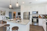 This single-story residence located on Spout Springs Road in Braselton, Georgia, offers a thoughtfully designed layout with a clean, contemporary aesthetic carried consistently throughout each room. The kitchen serves as a central highlight, featuring white shaker-style cabinetry, granite countertops, a subway tile backsplash, stainless steel appliances including a refrigerator, range, microwave, and dishwasher, and wood-look flooring that adds warmth to the bright, functional space. A kitchen island provides additional counter space and casual dining opportunities.

The dining area benefits from an abundance of natural light, with multiple windows framing the space and offering views of the surrounding neighborhood. The living room is open and airy, with neutral walls, wood-look flooring, and ample room for comfortable furnishings.

The bedrooms feature plush carpet, generous natural light from well-positioned windows, and direct access to closet space. The primary bathroom includes wood-look flooring, a granite-topped vanity with white cabinetry, and a walk-in closet. A secondary bathroom mirrors this refined style with a tub-shower combination and matching finishes. Throughout, the home maintains a cohesive palette of whites and neutral tones, creating a calm and inviting atmosphere.