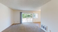 This single-floor residence offers a well-organized layout designed for comfortable everyday living. The living room serves as the heart of the space, featuring wall-to-wall carpet, neutral cream-toned walls, and a textured popcorn ceiling. A large sliding glass door opens directly onto a private balcony, flooding the room with natural light and framing lush tree views. A secondary window further enhances the brightness of this open area. A built-in wall heater provides practical climate control.

The galley-style kitchen is efficiently designed with white cabinetry above and below, granite-look laminate countertops, a stainless steel sink, and white appliances including an electric range and a full-size refrigerator. Warm-toned tile flooring ties the space together and adds a clean, easy-to-maintain finish.

The bedrooms are carpeted and generously sized, each featuring neutral walls and a textured ceiling. One bedroom benefits from a window with views of the surrounding neighborhood and greenery, while another connects to a hallway with closet access.

The bathroom is clean and functional, finished with the same warm tile flooring as the kitchen. It includes a double-sink vanity with granite countertops, white cabinetry, a full tub-shower combination with white tile surround, and a small privacy window for ventilation.