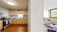 Located at 2701 S Indiana Ave in Chicago's South Loop neighborhood, this two-floor residence offers a functional and comfortable layout across its living spaces. The kitchen is outfitted with light maple cabinetry, generous counter space, a stainless steel gas range, and hardwood flooring, providing a practical and attractive cooking environment. Adjacent to the kitchen, the dining area features carpeted flooring and a window that brings in natural light, creating an inviting setting for meals. The living room is bright and open, highlighted by large windows offering views of the surrounding Chicago cityscape and greenery. A built-in niche adds a subtle architectural detail to the space. The bedroom is well-sized, featuring plush carpeting, a large window with treetop and street views, and dual closets with bifold doors and built-in shelving for ample storage. The bathroom includes hardwood-style flooring, a vanity with light cabinetry, and a shower-tub combination. Hardwood flooring flows through the main entry and kitchen areas, while carpet runs through the living, dining, and sleeping spaces. A staircase connects the two floors, completing the multi-level layout of this Chicago residence.