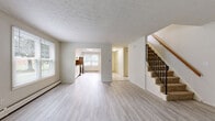 Located at 145 Harbor Pond Dr in Meriden, CT, this multi-level home offers a well-organized layout spread across three floors plus a basement. The main level features an open-plan living and dining area with light gray laminate hardwood flooring, neutral white walls, and a textured ceiling. Natural light flows in through multiple windows, creating a bright and airy atmosphere. The kitchen is adjacent to the living area and includes stainless steel appliances, white cabinetry, and a window overlooking the outdoors. A carpeted staircase with a wood handrail and black metal balusters connects all levels. The upper floors house two bedrooms, each carpeted and generously sized. The primary bedroom features vaulted ceilings, large windows, and ample natural light, enhancing its sense of space. It is complemented by dual closets. Multiple closets throughout the home provide abundant storage. Three full bathrooms serve the home, including one with a walk-in shower stall and white tile flooring. The unfinished basement offers additional utility space with a painted concrete floor, exposed framing, and mechanical systems. Wire-rack shelving in the closets adds practical organization throughout this functional and well-laid-out residence.
