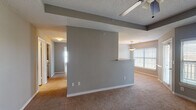 This single-floor residence offers a practical and comfortable layout designed for everyday living. The open living and dining areas are defined by a central partial-wall divider with a pass-through ledge, creating a natural separation of spaces while maintaining an open feel. Neutral gray walls, plush carpeting, and textured ceilings are consistent throughout, giving the home a cohesive aesthetic. Ceiling fans are installed in the main living areas and bedrooms, ensuring comfort year-round. Large windows with horizontal blinds allow natural light to fill the living and dining spaces.

The galley-style kitchen features white cabinetry, granite-look countertops, and stainless and black appliances including a refrigerator, range, and microwave. Wood-look flooring runs through the kitchen, providing a clean contrast to the carpeted areas throughout the rest of the home.

The bedrooms are generously sized with soft carpeting, neutral walls, and ceiling fans. Each room offers ample space and connects to a well-lit hallway. The bathrooms are finished with granite countertops, dual sinks, full-size tub and shower combinations with classic black-and-white checkered tile accents, large mirrors, and elegant multi-bulb light fixtures, adding a refined touch to the functional spaces.