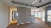 This single-floor residence offers a practical and comfortable layout designed for everyday living. The open living and dining areas are defined by a central partial-wall divider with a pass-through ledge, creating a natural separation of spaces while maintaining an open feel. Neutral gray walls, plush carpeting, and textured ceilings are consistent throughout, giving the home a cohesive aesthetic. Ceiling fans are installed in the main living areas and bedrooms, ensuring comfort year-round. Large windows with horizontal blinds allow natural light to fill the living and dining spaces.

The galley-style kitchen features white cabinetry, granite-look countertops, and stainless and black appliances including a refrigerator, range, and microwave. Wood-look flooring runs through the kitchen, providing a clean contrast to the carpeted areas throughout the rest of the home.

The bedrooms are generously sized with soft carpeting, neutral walls, and ceiling fans. Each room offers ample space and connects to a well-lit hallway. The bathrooms are finished with granite countertops, dual sinks, full-size tub and shower combinations with classic black-and-white checkered tile accents, large mirrors, and elegant multi-bulb light fixtures, adding a refined touch to the functional spaces.