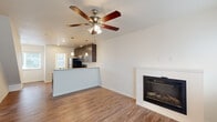 This two-story, two-bedroom, two-bathroom home is thoughtfully designed to maximize every square foot across two well-proportioned floors. The main level features an open-concept living area and kitchen, where warm wood-look flooring flows throughout. A built-in fireplace with a clean white surround anchors the living room, complemented by a ceiling fan overhead. The kitchen is outfitted with dark espresso cabinetry, stainless steel appliances including a refrigerator, range, microwave, and dishwasher, and light quartz-style countertops. A raised peninsula with pendant lighting above separates the kitchen from the living area, offering both casual dining and additional prep space. Natural light enters through windows dressed with horizontal blinds. Upstairs, two bedrooms are finished with plush carpeting, ceiling fans, and windows that bring in natural light. The primary bedroom features wood-look flooring and dual windows. The bathrooms are finished with matching dark cabinetry, dual under-mount sinks, and light countertops, maintaining a cohesive aesthetic throughout. A hallway and staircase connect the two levels seamlessly, completing this well-appointed and efficiently designed home.