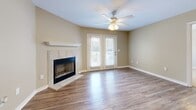 Located at 679 E Michigan Ave in Foley, Alabama, this single-story, 2-bedroom, 2-bathroom home offers a well-organized layout across a comfortable footprint. The living room serves as the heart of the home, highlighted by a tile-surround fireplace with a classic white mantel, warm wood-look flooring, a ceiling fan, and a set of French doors that invite natural light and provide outdoor access. Adjacent to the living room, the dining area features the same durable flooring and is appointed with an elegant chandelier. The galley-style kitchen is efficiently designed with white shaker cabinets, light countertops, a dark tile backsplash, and black appliances, with a pantry providing additional storage. Both bedrooms are carpeted and feature ceiling fans, with natural light supplied by large windows. The spacious primary bedroom includes a walk-in closet with built-in shelving. The two bathrooms are consistently finished with white vanity cabinetry, wood-look flooring, and tub-shower combinations. Neutral, warm-toned walls flow throughout the entire home, creating a cohesive and inviting atmosphere that is both functional and comfortable.