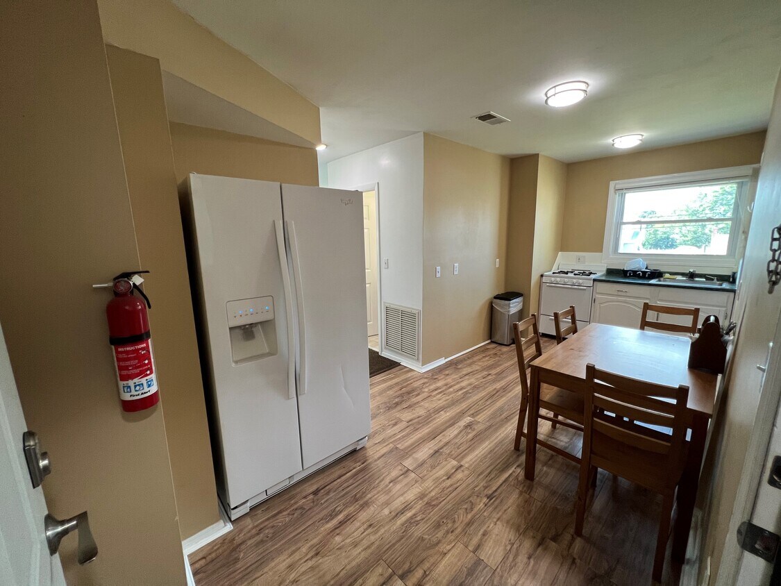 Cocina con refrigerador grande y mesa de comedor. - 100 Manning Pl