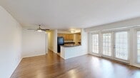 Located at 8800 Queensmere Place in Richmond, Virginia, this single-floor, 2-bedroom, 2-bathroom residence offers 850 square feet of well-organized living space. The open-concept kitchen and living room serve as the heart of the home, featuring warm hardwood flooring, light wood cabinetry, dark granite-style countertops, and black appliances including a gas range, built-in microwave, and refrigerator. A peninsula with a double sink adds additional workspace. The living area benefits from abundant natural light through a large set of French doors flanked by full-length windows, opening to the outdoors. Both bedrooms are carpeted and equipped with ceiling fans; the primary bedroom measures 170 square feet. The two bathrooms include a full bath with a tub/shower combo and a second bathroom featuring a pedestal sink and mirror. A dedicated laundry room houses a washer and dryer alongside an in-unit water heater, finished with tile flooring. A hallway and closet complete the layout. The unit's clean, neutral palette and functional design make it a practical and comfortable living space.