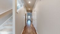 This two-story home in Bentonville, Arkansas offers a well-organized layout across two floors, with the main level housing the kitchen, living room, and supporting spaces, while the upper level accommodates the majority of the bedrooms and bathrooms. The main floor features an open-concept kitchen and living area finished with rich hardwood-style flooring and crown molding throughout. The kitchen is equipped with white shaker cabinetry, granite countertops, a peninsula with an undermount sink, and stainless steel appliances including a refrigerator, range, microwave, and dishwasher. The adjacent living room receives natural light through multiple windows fitted with blinds and features a ceiling fan overhead.

Upstairs, a straight staircase leads to a hallway connecting the four bedrooms and bathrooms. Each bedroom features neutral carpet, ceiling fans with lighting, and ample natural light. The primary bedroom includes access to a walk-in closet and a private bathroom. Additional bedrooms share well-appointed bathrooms outfitted with tub-shower combinations and light tile flooring. A consistent neutral color palette, white trim, and panel doors carry throughout both floors, giving the home a clean, cohesive aesthetic.