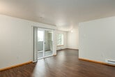 This single-floor residence offers a clean, functional layout designed for comfortable everyday living. The open living and dining area is finished with rich, dark hardwood-style flooring that flows throughout the main living spaces, complemented by neutral wall tones and warm wood baseboards. Sliding glass doors lead to a private balcony, filling the living area with natural light and providing views of the surrounding greenery.

The kitchen features a peninsula breakfast bar, light wood cabinetry with ample storage, a white appliance suite including a refrigerator and electric range, and under-cabinet lighting. Its open design connects seamlessly to the main living area, making it ideal for daily use.

The bedrooms are carpeted for comfort and include closet storage, with windows that bring in natural light and neighborhood views. Baseboard heating is present throughout, ensuring year-round comfort.

Two bathrooms serve the residence, each featuring warm wood vanity cabinetry, solid surface countertops, large mirrors, and hardwood-style flooring. One bathroom includes a shower/tub combination, while both are equipped with grab bars for added convenience and accessibility. The overall ambiance of the space is bright, clean, and move-in ready.