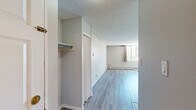 Located in the lively 17th Avenue SW neighbourhood of Calgary, this efficiently designed unit offers a practical and functional single-floor layout. The open-concept living space is finished with light grey laminate flooring throughout, neutral grey walls, and a textured ceiling, creating a clean and understated aesthetic. A large window in the living area allows natural light to fill the space, complemented by a baseboard heating system that runs along the perimeter walls for year-round comfort.

The kitchen is defined by a peninsular breakfast bar with a granite-style countertop, providing a natural division between the cooking and living zones. White cabinetry with a classic tile backsplash and white appliances, including an electric range and refrigerator, keep the kitchen bright and practical. Overhead flush-mount lighting ensures the area is well illuminated. A closet near the entry provides additional storage, and the front entry door is conveniently accessible from the kitchen zone.

The full bathroom features warm-toned tile flooring, a tiled shower-tub surround with a decorative border accent, a white vanity with storage cabinetry, and a large mirror. The overall unit offers a straightforward, functional layout well-suited for efficient urban living in a prime Calgary location.