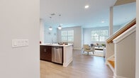 Located at 408 Lighthouse Lane in East Lyme, Connecticut, this two-story residence offers a well-designed layout with contemporary finishes across both levels. The main floor centers around an open-concept living and dining area, where light hardwood-style flooring flows seamlessly throughout. The kitchen is equipped with stainless steel appliances, including a range, over-the-range microwave, dishwasher, and refrigerator, complemented by two-tone cabinetry featuring dark lower cabinets and white uppers, topped with white countertops. A kitchen island with pendant lighting adds both function and style. The adjacent dining area is bright and inviting, with large windows framing outdoor greenery. The living room benefits from multiple windows and direct access to the outdoors through a glass-panel door. Upstairs, the bedrooms feature plush carpeting and ample natural light. The primary bathroom includes a double-sink vanity with dark wood cabinetry and tile flooring. A dedicated laundry area with a full-size washer and dryer adds everyday convenience. Throughout, the home maintains a clean, neutral palette with modern fixtures, creating a bright and cohesive living environment.
