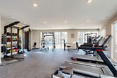 Located at 277 Clifton St SE in Atlanta, GA, this well-appointed fitness center offers a comprehensive workout facility across a single, open floor. The space is designed to accommodate a wide range of exercise routines, with a thoughtful layout that maximizes both functionality and comfort.

Large floor-to-ceiling windows line the perimeter of the room, flooding the interior with abundant natural light and providing views of the outdoor pool area and surrounding community. The bright, airy atmosphere is complemented by a neutral color palette of whites and warm grays, recessed ceiling lighting, and durable rubber flooring suited for high-impact training.

The cardio zone is well-stocked with multiple treadmills, elliptical machines, water rowers, and Echelon stationary bikes equipped with interactive screens. The strength training area features a multi-station cable machine, a power rack with a pull-up bar, adjustable benches, and a punching bag. A dedicated functional training section includes TRX suspension systems, kettlebells in varying weights, medicine balls, and a ball rack for organized storage. A mirrored wall enhances the free weights area, supporting form-focused training. A water fountain is conveniently located within the space. Direct access to the outdoor area is available through a glass door, connecting the fitness center seamlessly to the broader amenity spaces.