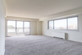 Located at 601 Pembroke Ave in Norfolk, Virginia, this single-floor residence offers a thoughtfully laid-out interior with generous living spaces and an abundance of natural light. The expansive living room is a standout feature, boasting large sliding glass doors and wide windows that frame sweeping outdoor views of the surrounding cityscape and waterfront, creating a bright and open atmosphere. Plush carpeting flows throughout the main living areas and bedrooms, adding warmth and comfort underfoot, while tile flooring transitions through the entryway and wet areas. The kitchen is efficiently designed with white cabinetry, a gas cooktop, a wall oven, and ample counter space, providing a practical and clean workspace. Two bedrooms are each equipped with ceiling fans and closet storage, offering comfortable and functional retreats. The bathrooms are finished in classic white tile — one featuring a full vanity with louvered cabinet doors and mosaic tile flooring, and the other showcasing a glass-enclosed shower with coordinating mosaic tile detailing. A tiled entryway hallway connects the rooms with ease. Overall, the space presents a clean, neutral palette with practical finishes throughout, ideal for comfortable everyday living.