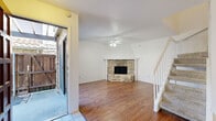 This two-story home offers a practical and comfortable layout across two floors, with three bedrooms, three bathrooms, and a collection of well-defined living spaces. The main floor sets an inviting tone with its warm hardwood-style flooring throughout the living and dining areas. The living room is a standout, centered around a striking stone fireplace with a classic mantle, complemented by a ceiling fan and access to an outdoor area through a sliding glass door. A carpeted staircase with white railings connects the two floors, and a dedicated closet off the main living area adds convenient storage. The kitchen is efficiently arranged with white cabinetry, a full suite of white appliances including a range, over-the-range microwave, and refrigerator, all set atop light tile flooring. The upper floor is home to the bedrooms, each finished with plush carpet and ceiling fans. The generously sized primary bedroom includes an en-suite bathroom, while the additional bedrooms offer closets and natural light through bright windows. The bathrooms throughout are clean and functional, featuring tile flooring and white cabinetry. Textured ceilings and neutral white walls create a bright, cohesive aesthetic throughout the entire home.