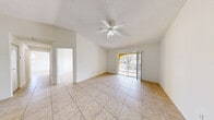 Located at 5500 NW 61st St in Coconut Creek, Florida, this 2-bedroom, 1-bathroom home offers a bright and functional single-floor layout with consistent tile flooring throughout. The open living area is highlighted by vaulted ceilings, a ceiling fan with light kit, and a sliding glass door that opens to a private balcony, filling the space with natural light and outdoor views. The kitchen is well-appointed with rich dark wood cabinetry, granite countertops, a full suite of white appliances including a refrigerator, electric range, and over-the-range microwave, along with a stainless steel sink. Both bedrooms are generously sized, each featuring ceiling fans, large windows with blinds that bring in ample natural light, and tile flooring. The spacious primary bedroom includes a closet with louvered bifold doors. The full bathroom is cleanly finished with a granite-top vanity matching the kitchen's cabinetry style, tile-surround tub and shower combination, and tile flooring. A hallway connects the main living spaces efficiently. Textured ceilings are present throughout, adding a classic Florida residential feel to the overall design.