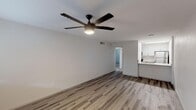 Located at 1350 E Northern Ave in Phoenix, AZ, this single-floor unit offers a clean, modern aesthetic throughout its well-organized layout. The open living area is finished with durable wood-look vinyl flooring and anchored by a sleek, multi-blade ceiling fan that provides both style and airflow — a practical feature well-suited to the Arizona climate. The space flows naturally toward the kitchen, which is designed in a galley configuration featuring crisp white cabinetry, granite-look countertops, and stainless steel appliances including a refrigerator and range. Light-toned flooring in the kitchen complements the bright, white cabinetry for a fresh, contemporary feel. The bedrooms are finished with plush carpeting and feature window blinds that allow for natural light while maintaining privacy. Each bedroom includes its own ceiling fan, adding comfort and functionality. The neutral color palette used throughout — from the white walls to the warm-toned flooring — creates a cohesive and inviting atmosphere. The floor plan, as seen from the dollhouse view, reflects a practical and efficient use of space, with clearly defined living, kitchen, and sleeping areas that offer both comfort and ease of use.