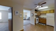 This single-floor space is designed with a practical, open layout that connects key living areas in a cohesive and functional arrangement. A central hallway acts as a transition zone, decorated with two framed geometric art pieces that add a subtle stylistic touch to the neutral, cream-colored walls.

To one side, the kitchen is equipped with wooden cabinetry offering ample storage, a white electric range, an overhead microwave, and a countertop workspace. A ceiling fan with an integrated light fixture provides both ventilation and illumination. The flooring features a checkered tile pattern that adds visual interest to the cooking space. A decorative "kitchen" sign and greenery atop the cabinets lend a homey character to the room.

Through the hallway, the living area comes into view, featuring plush carpeting, a pair of patterned accent chairs, and a floor lamp that creates a warm, inviting atmosphere. A decorative round mirror adorns the wall, enhancing the sense of depth in the space. The overall ambiance is calm and welcoming, with consistent neutral tones and understated décor tying each area together seamlessly.