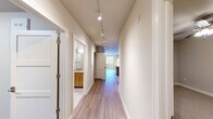 This single-level residence in Cedarburg, Wisconsin, offers a thoughtfully designed floor plan that balances comfort and functionality across a generously sized living space. The interior is unified by light-toned wood-style flooring throughout the main areas and hallways, complemented by neutral warm-beige walls that create a bright, cohesive aesthetic.

The kitchen is a standout feature, equipped with stainless steel appliances including a refrigerator, range, and microwave. Warm wood cabinetry pairs with granite countertops and a peninsula with a built-in sink, making the space equally suited for cooking and casual dining. The kitchen flows naturally into the living area, which benefits from a track lighting system, a large window, and a sliding glass door opening to a private balcony with outdoor views.

The primary bedroom is spaciously proportioned and features two closets with sliding panel doors, providing ample storage. The second bedroom is finished with plush carpet, a ceiling fan, and a window overlooking the surroundings. Both bathrooms are well-appointed, with one featuring a tiled tub-shower combination, granite vanity countertops, and wood cabinetry. The hallway is lined with track lighting, connecting all rooms efficiently throughout the residence.
