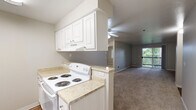 This three-bedroom, one-bathroom residence in Seattle, WA offers a practical and comfortable single-floor layout. The open-concept kitchen and living area serves as the heart of the home. The kitchen features white cabinetry, light laminate countertops, a white electric coil-burner range, a full-size refrigerator, a stainless steel sink, and wood-style flooring — all flowing seamlessly into the carpeted living room. The living room is highlighted by a tile-surround fireplace, a ceiling fan, and a sliding glass door that opens to a balcony with lush greenery views, filling the space with natural light. The three bedrooms are carpeted and serviced by baseboard heating, with windows offering leafy outdoor views. The primary bedroom provides a comfortable amount of space for everyday living. The full bathroom includes a soaking tub with a shower and curtain rod. A hallway connects the main living areas to the bedrooms and closet, supporting an efficient flow throughout the unit. The textured ceilings and neutral gray and beige tones throughout create a clean, cohesive aesthetic. This residence is ideally suited for those seeking a functional layout in the Seattle area.