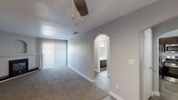 Located at 4700 W Rochelle Ave in Las Vegas, NV, this two-bedroom, one-bathroom unit offers a well-organized single-floor layout designed for comfortable everyday living. The living room serves as the heart of the home, featuring a corner fireplace with a black surround and a built-in arched niche above the mantle, plush carpet underfoot, and a sliding glass door with vertical blinds that allows natural light to fill the space. A ceiling fan adds to the comfort of the room. The kitchen is equipped with a double-basin stainless steel sink set into a light-toned countertop, with a window overlooking greenery that brings in pleasant natural light. Wood-look tile flooring runs through the kitchen and hallways, providing a clean contrast to the carpeted rooms. The primary bedroom is generously sized, offering ample space, a closet, and a window for natural light. The second bedroom also features carpet, a window with blinds, and a sliding closet. An arched doorway adds a charming architectural detail leading into the bathroom, which includes a full soaking tub with white tile surround. Hallways connect the rooms efficiently, completing this practical and comfortable Las Vegas residence.