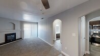 Located at 4700 W Rochelle Ave in Las Vegas, NV, this two-bedroom, one-bathroom unit offers a well-organized single-floor layout designed for comfortable everyday living. The living room serves as the heart of the home, featuring a corner fireplace with a black surround and a built-in arched niche above the mantle, plush carpet underfoot, and a sliding glass door with vertical blinds that allows natural light to fill the space. A ceiling fan adds to the comfort of the room. The kitchen is equipped with a double-basin stainless steel sink set into a light-toned countertop, with a window overlooking greenery that brings in pleasant natural light. Wood-look tile flooring runs through the kitchen and hallways, providing a clean contrast to the carpeted rooms. The primary bedroom is generously sized, offering ample space, a closet, and a window for natural light. The second bedroom also features carpet, a window with blinds, and a sliding closet. An arched doorway adds a charming architectural detail leading into the bathroom, which includes a full soaking tub with white tile surround. Hallways connect the rooms efficiently, completing this practical and comfortable Las Vegas residence.