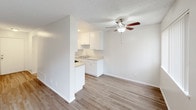 This two-story residence is designed with a clean, neutral aesthetic that creates a bright and functional living environment. The main level features wood-style hard flooring that flows through the living and dining areas, complemented by a ceiling fan with integrated lighting to promote air circulation and comfort. The kitchen is positioned adjacent to the living area and is equipped with white cabinetry, light stone-finish countertops, a gas range, and a stainless steel refrigerator. A pass-through counter connects the kitchen to the main living space, enhancing the open feel of the layout. A hallway leads from the kitchen toward additional rooms and bathroom facilities. One full bathroom on this level includes a tub-shower combination with a curved curtain rod, a vanity with matching countertops, and wood-look tile flooring. A secondary water closet provides an additional convenience. The upper level features carpeted bedrooms with textured ceilings, large windows that allow natural light to fill the space, and views of the surrounding exterior. The staircase connecting both floors is centrally located, making navigation between levels straightforward. Throughout, the space maintains a consistent, understated palette of whites and warm neutrals.