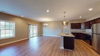 Located at 48 Bavarian Wy in Altamont, NY, this single-floor home offers a thoughtfully designed open-concept layout that seamlessly connects the kitchen, dining, and living areas. The kitchen is a standout feature, boasting rich dark cabinetry, granite countertops, a center island with a built-in sink, and a full suite of stainless steel appliances including a range, microwave, and refrigerator. Warm hardwood-style flooring runs throughout the main living spaces, complementing the neutral toned walls and recessed lighting. The living and dining area is generously proportioned, filled with natural light from large windows and sliding glass doors that open to the outdoors. A classic chandelier adds an elegant touch overhead. The bedrooms are spacious and well-lit, each featuring ceiling fans, hardwood-style flooring, and ample closet space. The primary bathroom is appointed with a dual-sink granite vanity, dark cabinetry, and tile flooring, while a second full bathroom mirrors the same quality finishes with a single vanity and tile floors. A convenient stacked in-unit washer and dryer adds everyday practicality. The home presents a clean, modern aesthetic throughout, making it a comfortable and functional living space.