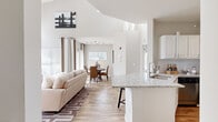 Located at 1503 Watkins Ln in Naperville, IL, this two-story home showcases a bright, open-concept layout with a seamless flow between the living, dining, and kitchen areas. The main living room impresses with dramatically vaulted ceilings and an abundance of natural light streaming through multiple large windows with blinds and curtain treatments. A tiled fireplace serves as the room's focal point, complemented by warm hardwood-style flooring throughout the main level. A staircase with carpet treads leads to the upper floor, reinforcing the home's spacious, airy feel.

The kitchen is well-equipped with white cabinetry, granite countertops, a granite-topped breakfast bar, and a full suite of stainless steel appliances including a gas range, built-in microwave, dishwasher, and refrigerator. The adjacent dining area offers access to an outdoor balcony, filling the space with natural light.

The bedrooms are carpeted and generously sized, each featuring ceiling fans, ample windows, and neutral tones. The primary bedroom is particularly spacious. Bathrooms feature white vanities, tiled tub-shower combinations with checkered accent tile, and clean, classic finishes throughout. This home offers a well-balanced combination of comfort, functionality, and style.