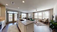 This thoughtfully designed single-floor residence offers a seamless open-concept layout that integrates the kitchen, dining, and living areas into one cohesive, light-filled space. The modern kitchen is a standout feature, showcasing crisp white shaker cabinetry extending to the ceiling, stainless steel appliances, a subway tile backsplash, and a generous center island with a quartz countertop and undermount sink — ideal for both meal preparation and casual entertaining. Wood-look flooring flows throughout the main living areas, anchoring the contemporary aesthetic.

The living room is bathed in natural light from a large bank of windows fitted with blinds and sheer curtains, and is complemented by a ceiling fan overhead. A dedicated dining area sits adjacent, framed by its own window with outdoor views. 

Both bedrooms are comfortably scaled, carpeted, and feature ceiling fans and windows that invite natural light. The primary suite connects to a well-appointed bathroom with a double vanity, tile flooring, a glass-enclosed shower, and direct access to a spacious walk-in closet with built-in shelving.

Throughout the residence, a neutral warm-gray palette, recessed lighting, and clean architectural lines contribute to a modern yet welcoming ambiance.