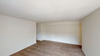 Located at 5301 S East St in Indianapolis, Indiana, this single-floor unit offers a well-organized layout designed for comfortable everyday living. The open living area is generously sized, featuring plush wall-to-wall carpeting, neutral cream-toned walls, and a ceiling fan that enhances airflow and comfort. Large sliding glass doors flood the space with natural light and provide direct access to an outdoor area, creating a bright and airy atmosphere throughout.

The galley-style kitchen is efficiently designed with ample white cabinetry on both sides, offering substantial storage and counter space. White appliances including a refrigerator and electric range complement the clean aesthetic, while hardwood-style flooring adds warmth underfoot. A double-basin stainless steel sink and an entry door at the rear of the kitchen add both function and convenience.

The carpeted bedrooms are quiet and comfortable, each featuring neutral walls and closet access. One bedroom includes a window with an exterior view, allowing natural light to brighten the room. The full bathroom is cleanly appointed with tile flooring, a vanity with under-sink storage, and a tub and shower combination accented by a window for natural ventilation. Overall, the space presents a clean, move-in-ready environment with a practical and cohesive design.