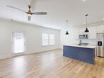 Located at 5020 Limelight Ln in Charlotte, NC, this two-story home offers 3 bedrooms and 4 bathrooms across two well-proportioned floors. The main level centers around a bright, open-concept kitchen and living area finished with light wood-look flooring and crisp white walls. The kitchen stands out with a striking blue island topped with a light countertop, white shaker cabinetry, stainless steel appliances, and black pendant lighting that adds a modern contrast. A ceiling fan and multiple windows fill the living space with natural light, while a rear door provides easy outdoor access. A light-filled hallway with large windows and a wood-railed staircase connects the main level to the upper floor. The upper level houses the generously sized primary bedroom and additional bedrooms, all with the same warm wood-look flooring and clean white finishes. A walk-in closet with wire shelving provides ample storage. The four bathrooms are consistently styled with white vanities, light countertops, wood-look flooring, and matte black fixtures. The attached garage features a concrete floor, automatic opener, and direct interior access, completing this well-designed Charlotte home.
