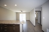 This single-floor residence offers a thoughtfully designed layout that balances functionality and comfort. The kitchen serves as a central highlight, showcasing rich dark espresso cabinetry paired with granite-style countertops that extend across generous prep and serving surfaces. A full suite of stainless steel appliances — including a refrigerator, microwave, range, and dishwasher — provides a modern, cohesive look. Light wood-tone flooring runs throughout the kitchen and main living areas, lending warmth and continuity to the open-concept floor plan. A wide breakfast bar peninsula connects the kitchen to the living space, making it ideal for casual dining or entertaining.

The bedroom features neutral-toned carpet, warm beige walls, a ceiling fan, and a window fitted with blinds that allows natural light to filter in. The bathroom includes a full soaking tub and shower combination in white, complemented by chrome fixtures and a paneled interior door that adds a subtle contemporary detail. The overall ambiance of the unit is clean, modern, and move-in ready, with consistent neutral tones and practical finishes throughout.