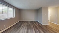 Located at 200 Mountain Avenue in Malden, MA, this three-bedroom, one-bathroom residence offers a practical and well-appointed single-floor layout. The space features wood-look plank flooring throughout, neutral-toned walls, and textured ceilings that lend a consistent, cohesive aesthetic from room to room.

The combined kitchen and living area serves as the heart of the home. The kitchen is outfitted with gray shaker-style cabinetry, light quartz countertops, a stainless steel gas range with an overhead exhaust hood, and a stainless steel refrigerator — providing a clean, modern look with functional workspace. The adjacent living area offers an open, airy feel with natural light filtering through the windows.

The generously sized primary bedroom benefits from dual windows that bring in ample natural light and provide exterior views, complemented by baseboard heating. The additional bedrooms are well-proportioned, each featuring wood-look flooring, neutral walls, and baseboard heating units. The bathroom includes a full-size soaking tub with a shower and white tile surround, maintaining a clean and bright finish. A dedicated laundry area is also accessible off the kitchen corridor. Overall, this residence delivers a clean, updated living environment with functional room configurations throughout.
