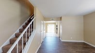 Located at 2001 Dawson Rd. in Albany, Georgia, this two-story residence offers a well-organized layout across both floors. The main level welcomes you with a wide entryway hallway featuring durable hardwood-style flooring that flows through the primary living areas. A carpeted staircase with white railings leads to the upper floor. The kitchen is outfitted with white cabinetry, dark granite-style countertops, a stainless steel refrigerator, stainless electric range with overhead microwave, and a dishwasher — all set on light tile flooring. An adjacent dining area benefits from a sliding glass door that opens to the outdoors, filling the space with natural light. A full bathroom on the main level features a tub-shower combination, wood-style flooring, white cabinetry, and a granite-topped vanity. The upper level hosts multiple carpeted bedrooms, each equipped with a ceiling fan and natural light provided by blinded windows. A half bathroom on the upper floor includes wood-style flooring and a granite-topped vanity. Throughout, warm beige walls and white trim create a consistent, neutral aesthetic. The thoughtful two-floor design offers clear separation between living and sleeping spaces.