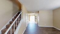 Located at 2001 Dawson Rd. in Albany, Georgia, this two-story residence offers a well-organized layout across both floors. The main level welcomes you with a wide entryway hallway featuring durable hardwood-style flooring that flows through the primary living areas. A carpeted staircase with white railings leads to the upper floor. The kitchen is outfitted with white cabinetry, dark granite-style countertops, a stainless steel refrigerator, stainless electric range with overhead microwave, and a dishwasher — all set on light tile flooring. An adjacent dining area benefits from a sliding glass door that opens to the outdoors, filling the space with natural light. A full bathroom on the main level features a tub-shower combination, wood-style flooring, white cabinetry, and a granite-topped vanity. The upper level hosts multiple carpeted bedrooms, each equipped with a ceiling fan and natural light provided by blinded windows. A half bathroom on the upper floor includes wood-style flooring and a granite-topped vanity. Throughout, warm beige walls and white trim create a consistent, neutral aesthetic. The thoughtful two-floor design offers clear separation between living and sleeping spaces.