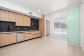 Located at 1140 S Normandie Ave in Los Angeles, this thoughtfully designed one-bedroom, one-bathroom unit offers a modern aesthetic throughout its efficiently organized single-floor layout. Light-toned luxury vinyl plank flooring flows seamlessly through every room, complementing the clean white walls and recessed lighting that keep the space bright and contemporary.

The open-plan kitchen and living area serves as the heart of the unit. The kitchen is well-appointed with flat-front light wood cabinetry, striking dark hexagonal tile backsplash, white quartz countertops, and a full suite of stainless steel appliances including a refrigerator, range, microwave, and dishwasher. Large sliding glass doors in the living area invite natural light and provide access to an outdoor space.

The bedroom is a calm, light-filled retreat featuring a frosted glass sliding door that enhances the modern feel while maximizing privacy. Two closets offer ample storage throughout the unit. A dedicated laundry area adds everyday convenience.

The bathroom is finished with a light wood vanity with drawer storage, a framed mirror, built-in open shelving tower, and a full soaking tub with shower. A hallway with an accessible electrical panel connects the living spaces efficiently. The overall design is clean, functional, and move-in ready.