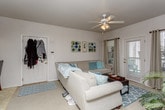 This single-floor residence offers a thoughtfully designed layout that balances comfort and functionality throughout. The living area serves as the heart of the home, featuring neutral-toned walls, soft carpeting, and a ceiling fan overhead. A large sectional sofa anchors the space, complemented by teal and turquoise accent pillows that carry a coastal color palette throughout. Framed wall art and natural light from nearby windows add warmth and character to the room. The living area flows seamlessly into a dedicated dining space, creating an open and connected feel ideal for entertaining.

The galley-style kitchen is bright and efficient, lined with white cabinetry on both sides and equipped with full appliances including a range, refrigerator, and microwave. Light tile flooring and ample counter space make this kitchen both practical and clean in appearance.

The primary bedroom is generously sized with plush carpeting, offering room for a full dresser arrangement and additional storage. A second bedroom doubles as a personal retreat and workspace, featuring a tufted headboard, coordinated wood furniture, and a dedicated study desk — ideal for productivity or relaxation. Both bedrooms maintain a warm, cozy ambiance with neutral tones. A dedicated in-unit laundry room with a full-size washer and dryer provides added convenience, rounding out this well-equipped home.