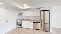 Located in London, Ontario, this efficiently designed one-bedroom, one-bathroom unit offers a clean, modern aesthetic throughout. Light hardwood-style flooring runs continuously across the open layout, complementing the bright white walls and contemporary finishes.

The kitchen is well-appointed with a full suite of stainless steel appliances, including a flat-top range, dishwasher, and a full-size fridge-freezer. White cabinetry extends to the ceiling, maximizing storage, while a recessed under-cabinet range hood and a single-basin sink with modern faucet complete the functional workspace.

The entryway is bright and welcoming, with recessed lighting and a built-in storage panel providing convenient organization from the moment you step inside.

The bedroom is a clean, rectangular space with crisp white walls and light flooring, offering a calm, neutral environment suitable for various furniture arrangements.

The bathroom features large-format grey tile flooring, a soaker tub with an overhead shower, a white vanity with a warm wood-tone countertop, integrated sink, and a mirrored medicine cabinet — delivering a tidy, functional design.

A private balcony extends the living space outdoors. The unit's straightforward layout and consistent modern finishes make it a practical and well-organized living space in the heart of London, Ontario.