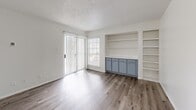 Located at 1930 W Rundberg Ln in Austin, TX, this one-bedroom, one-bathroom unit offers a well-organized single-floor layout with a thoughtful mix of hardwood-style and carpeted flooring throughout. The combined kitchen and living area serves as the heart of the home, featuring wood-style flooring that flows seamlessly between the two spaces. The living room stands out with built-in shelving and cabinetry in a muted blue-gray finish, providing ample display and storage space, along with a sliding glass door that opens to a private balcony and lets in generous natural light. The kitchen is equipped with gray cabinetry, light countertops, and a full suite of black appliances including a refrigerator, electric range, microwave, and dishwasher, complemented by a double-basin sink. The bedroom offers a comfortable and quiet retreat with soft carpeting, a ceiling fan with light fixture, and a window overlooking the outdoors. A dedicated closet provides additional storage. The bathroom features a tub-shower combination, a vanity with matching gray cabinetry and light countertop, hardwood-style flooring, and a mirrored medicine cabinet. Clean white walls and consistent finishes throughout give the space a cohesive, move-in-ready feel.