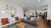 This single-floor residence in Plainfield, Indiana offers a thoughtfully designed open-concept layout with contemporary finishes throughout. The living area serves as the heart of the home, featuring recessed lighting, wood-look flooring, and an open sightline into the kitchen and dining space. Large windows allow natural light to fill the room, complementing the neutral gray palette on the walls.

The kitchen is well-equipped with two-tone cabinetry — white upper cabinets paired with gray lower cabinets — granite countertops, a stainless steel refrigerator, range, and microwave. A kitchen island with bar seating provides additional prep and dining space, while pendant lighting adds a modern touch overhead.

The primary bedroom is generously sized with a ceiling fan, access to natural light through a large window with vertical blinds, and warm wood-look flooring. The second bedroom also benefits from natural light and closet storage. Both bathrooms feature granite-topped vanities with gray cabinetry, tub-shower combinations with tiled or white surrounds, and wood-look flooring, maintaining the home's cohesive modern aesthetic throughout.