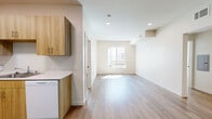 Located at 6940 Owensmouth Ave in the Canoga Park neighborhood of Los Angeles, this 3-bedroom, 1-bathroom unit offers a clean, modern aesthetic throughout its single-floor layout. Light-toned wood-look flooring runs continuously through every room, creating a cohesive and bright atmosphere enhanced by recessed lighting and crisp white walls.

The open-concept kitchen and living area forms the heart of the unit. The kitchen is well-appointed with warm wood-grain cabinetry lining both sides, white appliances including a range and dishwasher, a double sink, and ample counter space. The adjoining living area receives natural light through a sliding window, giving the space an airy, welcoming feel.

Three bedrooms offer comfortable accommodations, each with natural light from windows overlooking the surrounding neighborhood. The primary bedroom includes a sliding closet for organized storage, while additional closets throughout the unit provide further storage solutions.

The single bathroom is finished with a wood-toned vanity, a large mirror with overhead lighting, wood-look flooring, and a tiled shower-tub combination. A connecting hallway ties all rooms together efficiently. Throughout the unit, the design emphasizes clean lines, neutral tones, and functional simplicity, making it a well-organized and inviting living space.