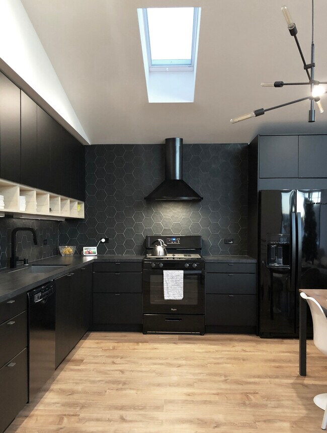 Chef's Kitchen with black stainless steel appliances, tile backsplash, quartz countertops, skylight. - 10815 Oregon Ave