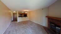 Located at 2260 Plymouth Rd in Minnetonka, MN, this single-floor unit offers a functional and straightforward layout suited for everyday living. The galley-style kitchen is well-equipped with black appliances, including an electric range with overhead microwave, a full-size refrigerator, and a dishwasher. Warm-toned wood cabinetry lines both sides of the kitchen, complemented by dark countertops and a double-basin stainless steel sink. Wood-look flooring runs throughout the kitchen, adding a clean, durable surface underfoot.

The kitchen opens via a breakfast bar with pendant lighting into a generously proportioned living area finished with wall-to-wall carpet. A small decorative shelf is mounted on one wall, and a brick hearth element is visible in the corner, adding a subtle architectural detail. The open sightlines between the kitchen and living space create a connected, easy-to-navigate floor plan.

The bedroom is carpeted and filled with natural light from a large window that overlooks lush greenery outdoors. The bathroom includes a tub-shower combination, a toilet, a single vanity with a wide mirror, and overhead lighting. Textured ceilings are present throughout the unit. The overall layout is compact yet practical.