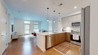 Located at 770 Thurber Dr. E in Columbus, Ohio, this well-appointed 2-bedroom, 2-bathroom residence offers a thoughtfully designed single-floor layout with modern finishes throughout. The open-concept living and kitchen area serves as the heart of the home, featuring warm hardwood-style flooring that flows seamlessly between spaces. The kitchen is a standout, outfitted with two-tone cabinetry — crisp white uppers paired with warm wood lowers — stainless steel appliances including a refrigerator, microwave, and range, plus a large center island with a white quartz countertop, undermount sink, and seating for two, illuminated by a trio of pendant lights overhead. The living room is bright and welcoming, with large windows and direct access to a private patio, filling the space with natural light. Both bedrooms are carpeted and serene, with generous windows fitted with roller shades. The spacious primary bedroom includes ample closet space with dedicated walk-in storage. The two bathrooms feature clean, minimalist finishes with wood-accented vanities and tile flooring. Additional conveniences include three closets, a dedicated laundry area, and a utility room, rounding out this efficiently planned and stylishly finished home.