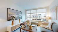 Located at 49 Fisk Street in Jersey City, NJ, this well-designed one-bedroom, one-bathroom residence offers a thoughtful layout across a single floor. Light wood flooring flows seamlessly throughout, lending warmth and continuity to every room.

The open-concept kitchen is outfitted with warm wood cabinetry, a dark tile backsplash, stainless steel appliances including a French-door refrigerator, and a central island with bar seating — ideal for both cooking and casual dining. The entry foyer is clean and functional, with direct access to the kitchen area.

The living room is bright and inviting, anchored by a large multi-pane window that fills the space with natural light and frames views of the surrounding Jersey City streetscape. The room comfortably accommodates a full seating arrangement and media setup.

The bedroom features a dedicated window with neighborhood views, a two-tone teal accent wall, and recessed lighting, creating a calm and restful retreat. The well-appointed bathroom includes a soaking tub with shower, a light wood vanity with dual drawers, a large framed mirror, dark upper cabinetry, built-in shelving niches, and large-format gray tile flooring — all finished with matte black fixtures for a cohesive modern aesthetic.