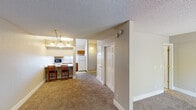 This two-floor residence offers a well-organized layout with a variety of functional spaces across both levels. The main floor opens into a carpeted living area centered around a tile-framed fireplace, creating a comfortable and inviting atmosphere. A hallway connects the living space to the kitchen and additional rooms, with textured walls and clean white trim throughout lending a classic, cohesive look.

The kitchen features a galley-style design with warm wood cabinetry lining both sides, light countertops, a white electric range, dishwasher, and a stainless steel sink. Ample upper and lower cabinet storage makes the space highly practical. Pendant lighting over a breakfast bar with seating provides a natural transition between the kitchen and the main living area.

The bathroom includes tile flooring, a wood-toned vanity with generous counter space, a framed mirror, and bright overhead lighting. A closet with sliding mirrored doors is accessible from the carpeted bedroom area.

The upper level showcases a distinctive vaulted, sloped ceiling that adds architectural character and a sense of openness. This versatile loft-style space overlooks the lower level via a railed landing and benefits from natural light filtering in through a set of exterior-facing doors, making it suitable for use as a bedroom, office, or lounge area.