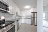 Located at 75 Eastdale Ave in Toronto's east end, this well-appointed one-bedroom, one-bathroom unit offers a bright and efficiently designed living space across a single floor. The open-concept layout connects the living room and kitchen, creating a seamless flow ideal for everyday living. Large floor-to-ceiling windows and a sliding glass balcony door flood the living area with natural light while framing views of the surrounding neighbourhood. Light-toned laminate flooring runs throughout the main living areas, complementing the clean, neutral grey-and-white colour palette.

The kitchen is thoughtfully updated with white shaker-style cabinetry, grey quartz countertops, a subway tile backsplash, and a full suite of stainless steel appliances including a refrigerator, electric range, over-the-range microwave, and dishwasher. Light tile flooring distinguishes the kitchen from the living area.

The generously sized primary bedroom features light laminate flooring, a built-in sliding-door closet, and a baseboard heater. The bathroom is finished with clean white subway tile surrounding a full bathtub and shower combination with chrome fixtures. Baseboard heating is present throughout, ensuring year-round comfort in this move-in-ready Toronto residence.